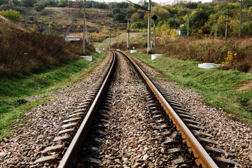 Metal old railway track at nature background with stones, grass and trees, ukrainian transportation way