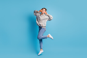 Full length photo portrait of kissing woman jumping up with headphones isolated on pastel blue colored background