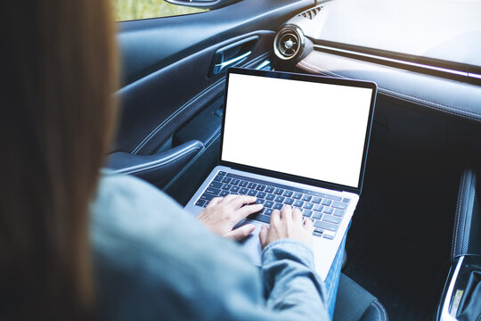 Mockup image of a woman using and typing on laptop computer with blank desktop screen in the car