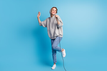 Photo portrait full body view of woman standing on one leg singing with mic in hood isolated on pastel blue colored background