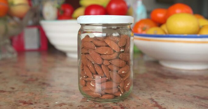 Bulk unshelled almonds in a glass jar on a kitchen table (eco-friendly)