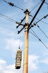 Concrete old railway pole with wires and weights for electric trains at blue sky background