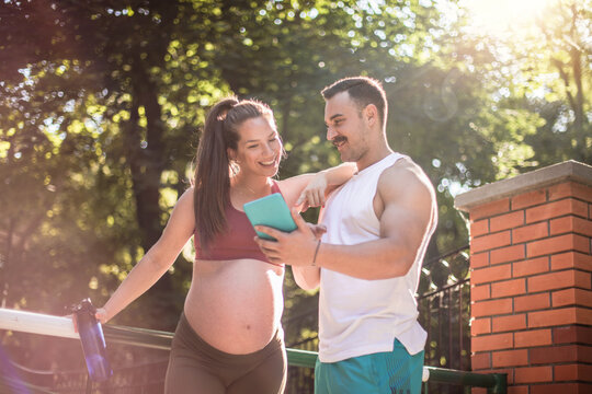 Sports couple standing outside and using digital tablet. - Powered by Adobe
