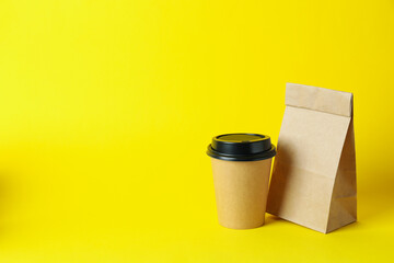 Paper cup and paper bag on yellow background