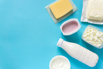 Fototapeta na wymiar Flat lay of dairy products. Milk, curd, sour cream, cheese and butter on blue background, copyspace