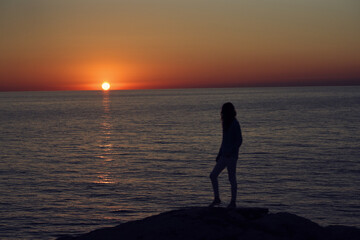 sunset in the mountains by the sea and a female silhouette on the beach