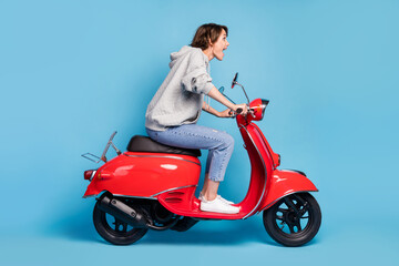 Obraz na płótnie Canvas Full length body size photo of crazy excited girl driving fast motorbike delivery isolated vibrant blue color background