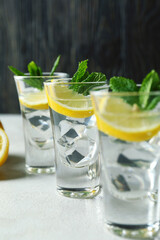 Shots with lemon slice and mint on white textured table