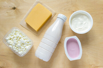 Flat lay of dairy products. Milk, curd, sour cream, cheese and yogurt on wooden background, top view