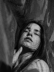 Portrait of a beautiful young woman in the shadow of the cloth on the direct sun. Artistic light.