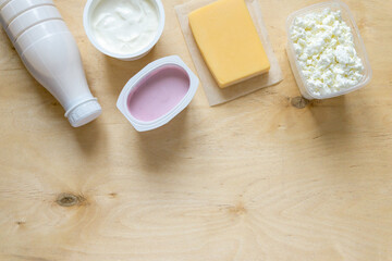 Fototapeta na wymiar Flat lay of dairy products. Milk, curd, sour cream, cheese and yogurt on wooden background, copyspace