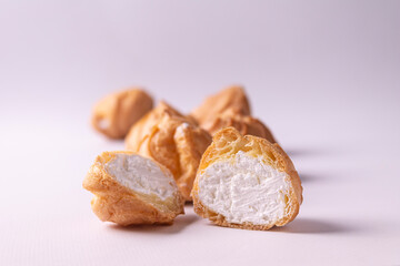 Profiteroles with cream on a white background.