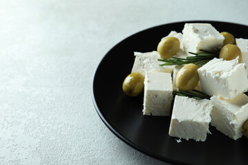 Plate with feta cheese, olives and rosemary on white textured background