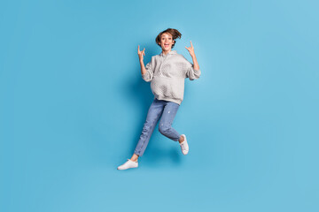 Fototapeta premium Full length body size side profile photo of girl jumping high showing heavy metal sign isolated vivid blue color background