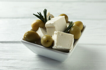 Bowl with feta, olives and rosemary on white wooden background