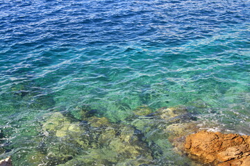 Fototapeta na wymiar La mer bleu émeraude avec de petites vagues et des rochers blancs et jaunes dans l eau
