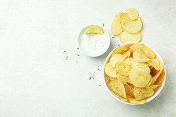 Tasty potato chips and sauce on white textured background