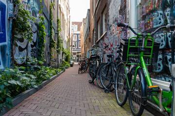 Row of bicycles parked in empty alley with graffiti on the walls