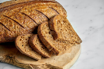 Delicious and tasty rye bread on a board on a marble background. Freshly baked bread