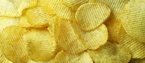 Tasty potato chips on whole background, close up