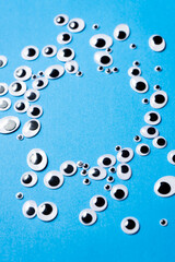 Toy eyes of different sizes scattered on a blue background