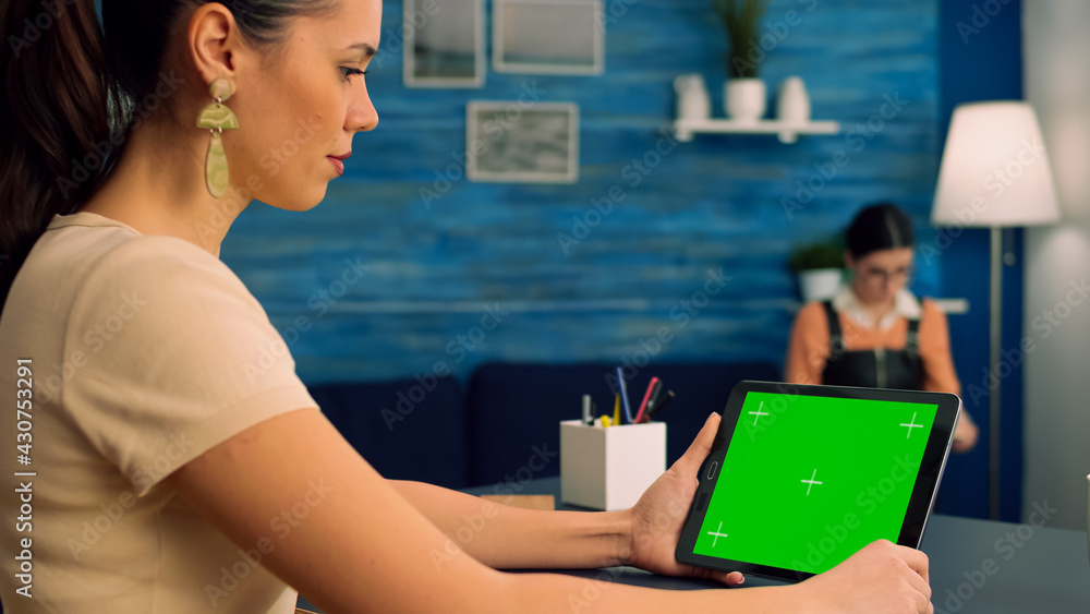 Poster woman working at office desk using mock up green screen tablet computer in landscape mode, watching 