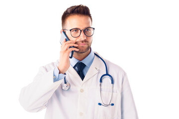 Male doctor studio portrait while talking on phone and standing at isolated background