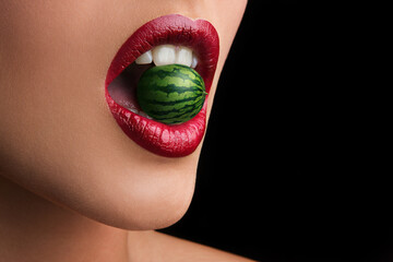 Tiny watermelon in open woman's mouth with red lips