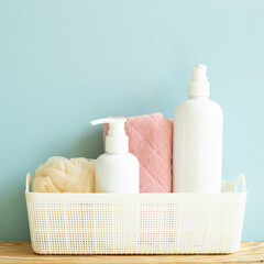 Skin care and spa concept. Bathroom bottle and towel in basket on wooden shelf. sky blue background