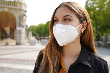 Close up portrait of young woman looking to the side while wearing protective mask KN95 FFP2...