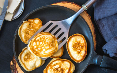 Small pancakes in a pan on a wooden board