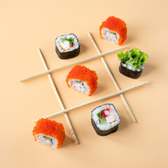 Tic tac toe game with sushi on orange background, creative concept sushi rolls. playing tic tac toe game