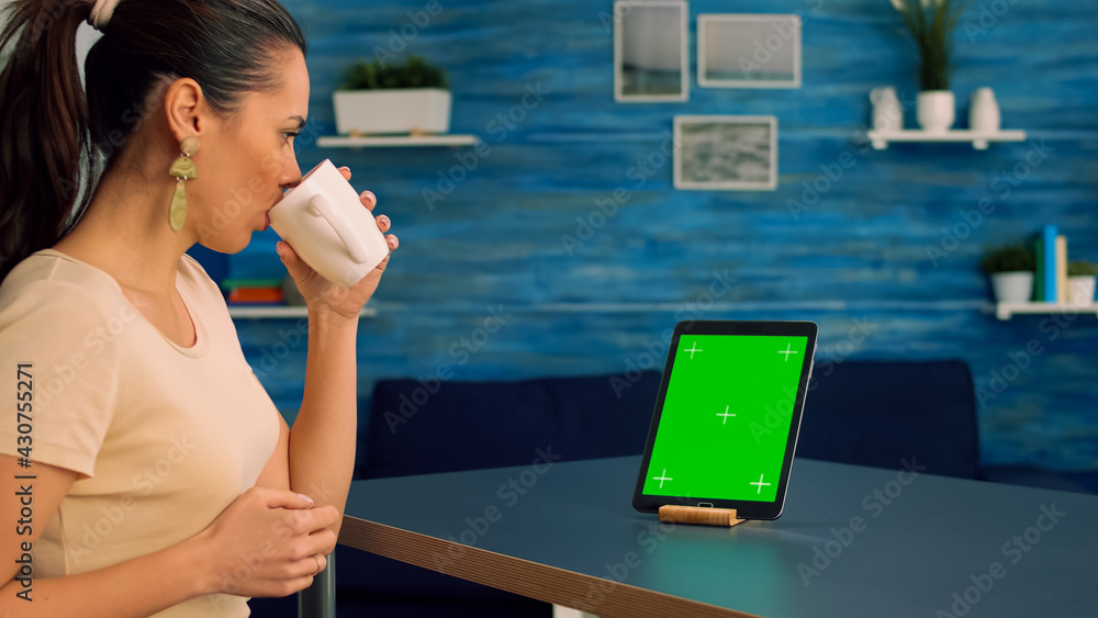 Poster freelancer looking at tablet computer display with mock up green screen chroma key while searching i