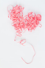 Pink heart curly ribbon on a white background with a place for text. 