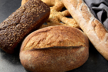 food, baking and cooking concept - close up of different bread on kitchen towel