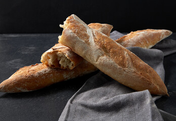 food, baking and cooking concept - close up of baguette bread on kitchen towel - obrazy, fototapety, plakaty