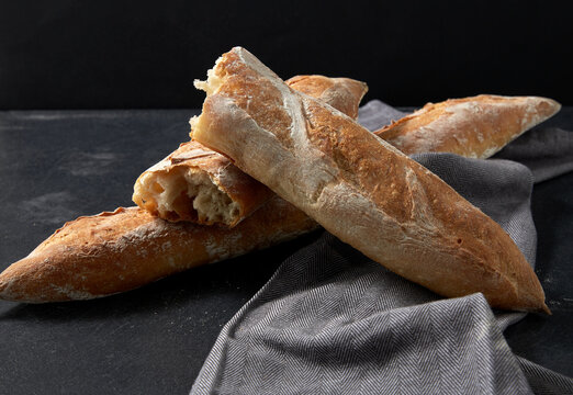 food, baking and cooking concept - close up of baguette bread on kitchen towel