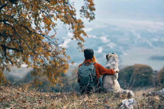 woman with dog sit on the ground in nature mountains