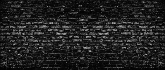 Fototapeta na wymiar Black old shabby brick wall wide texture. Dark gray rough brickwork. Aged block masonry backdrop. Gloomy grunge abstract panoramic background