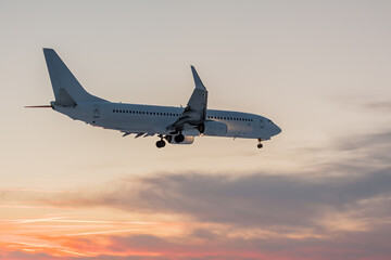 Fototapeta na wymiar The white plane lands against the sunset.