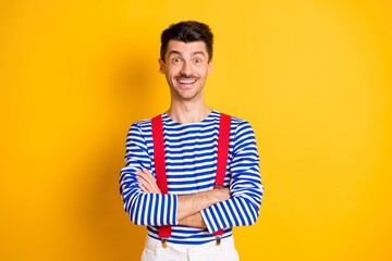 Photo of young handsome excited cheerful smiling positive man sailor with folded arms isolated on yellow color background
