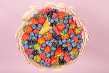 Edible bouquet of fresh berries, blueberries, raspberries, strawberries, hedgehog on a pink background. View from the top .Close-up .Concept of a useful gift, congratulations on the holiday.