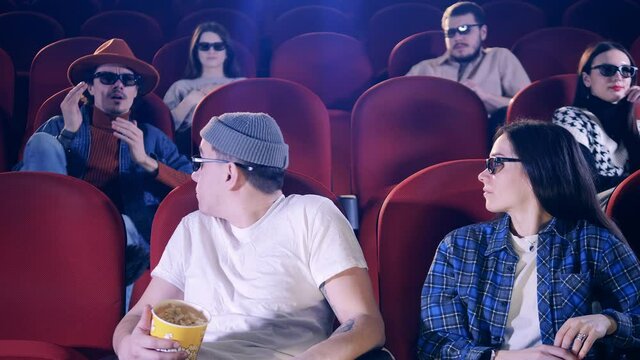 A man sneezes at the cinema with other people around