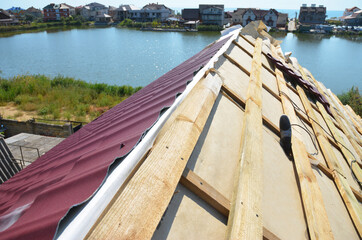 Metal roofing construction: A close-up on an unfinished roof ridge with a vapor, moisture barrier...