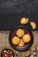 Homemade peanut cookies on a brown plate with raw peanuts in background