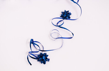 Shiny blue ribbon with bows on a white background.