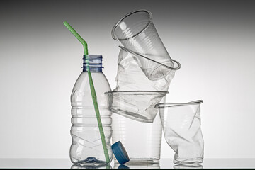 Set of used disposable tableware, gray background. The concept of ecology and recycling of plastic...