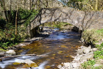 Fototapeta na wymiar Scenic view of a river flowing under a bridge on a hiking trail in countryside