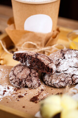 Fragrant coffee in a paper cup with foam and cinnamon and delicious cookies on a wooden tray. Place for text.