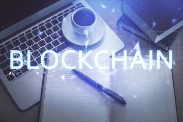 Blockchain theme hologram drawings over computer on the desktop background. Top view. Double...